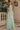 Back view of the Ladivine sage green chiffon one-shoulder maxi dress, highlighting the draped off-the-shoulder back and flowing fabric detail.