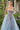 Close-up of Ladivine light blue tulle ballgown with sheer sweetheart corset bodice, delicate pink and blue floral embroidery, and spaghetti straps, modeled in a garden.