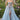 Ladivine light blue tulle ballgown with embroidered floral appliqués, sweetheart corset bodice, sheer skirt, and high leg slit, modeled outdoors in a garden setting.