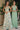 Ladivine sage floral print A-line gown with halter neckline and plunging deep V-neck, paired with a solid sage bridesmaid dress.