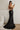 Woman in black sequin gown CH127 leaning against a wall